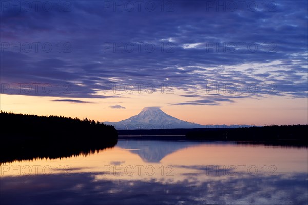 Reflection of clouds and mountain in river at sunset