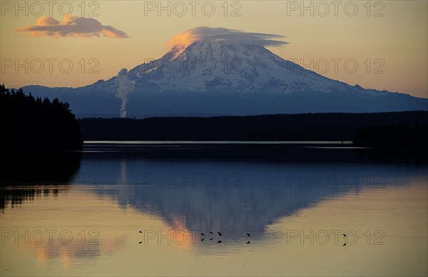 Reflection of clouds and mountain in river at sunset