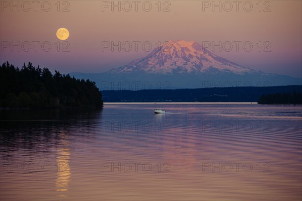 Boat in river near mountain under full moon