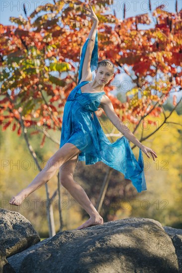 Caucasian ballerina dancing on rocks in park