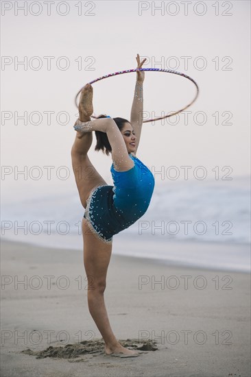 Caucasian gymnast practicing with hoop on beach