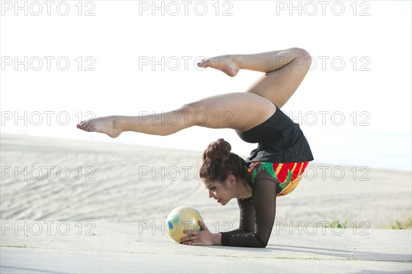 Caucasian gymnast balancing on arms on beach