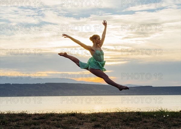 Caucasian ballerina jumping on beach