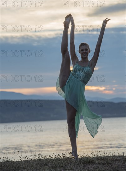 Caucasian ballerina dancing on beach at sunset