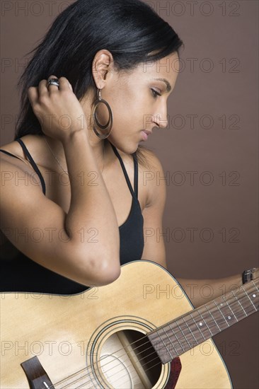 Mixed Race woman holding guitar