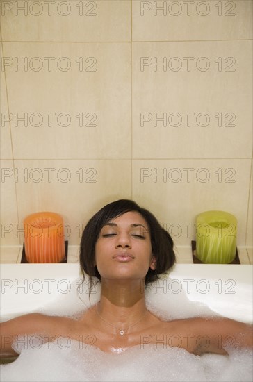 Mixed Race woman relaxing in bubble bath