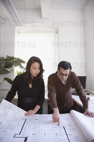 Multi-ethnic businesspeople looking at blueprints