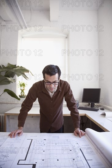 Hispanic businessman looking at blueprints