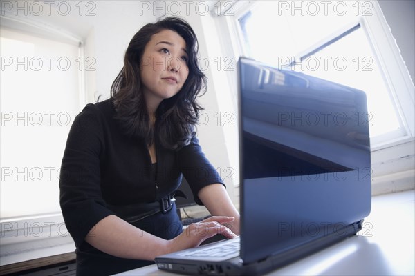 Asian businesswoman typing on laptop