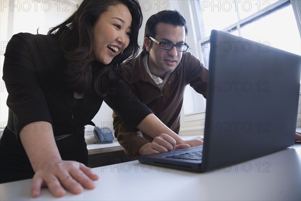 Multi-ethnic businesspeople looking at laptop