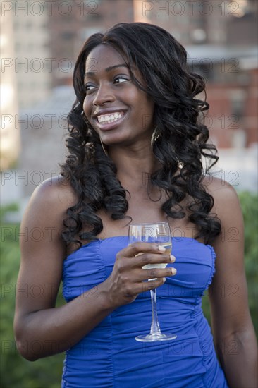 Glamorous African American woman drinking wine outdoors