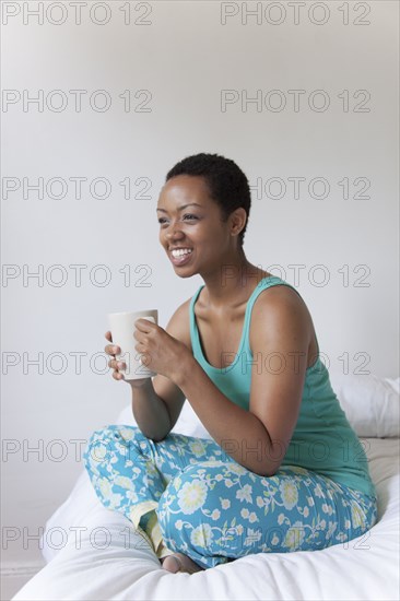 African American woman drinking coffee in bed