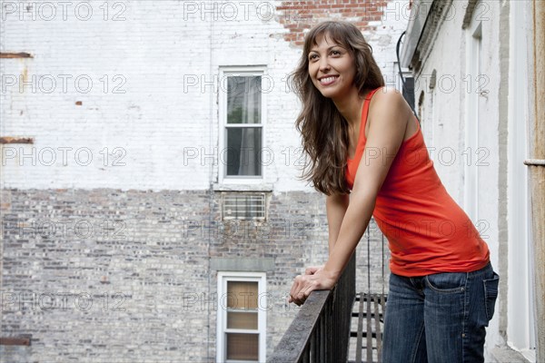 Mixed race woman leaning on fire escape railing