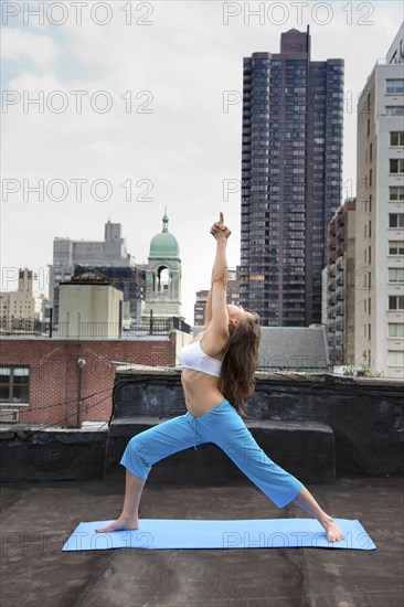 Mixed race woman practicing yoga on rooftop