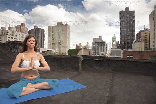 Mixed race woman practicing yoga on rooftop