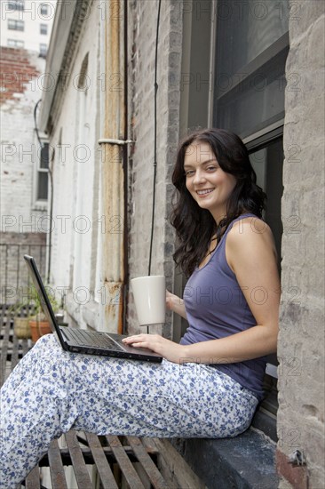 Woman using laptop on fire escape