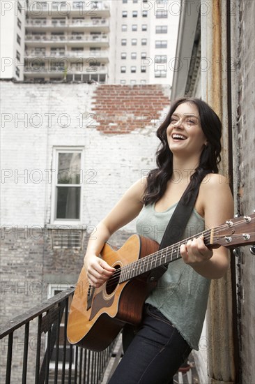 Woman playing guitar on fire escape