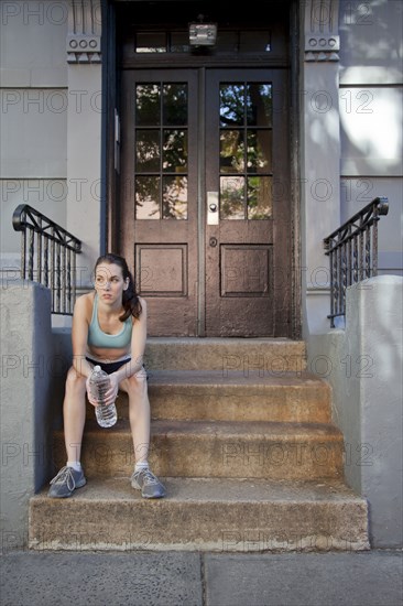 Caucasian woman relaxing with water bottle after exercise