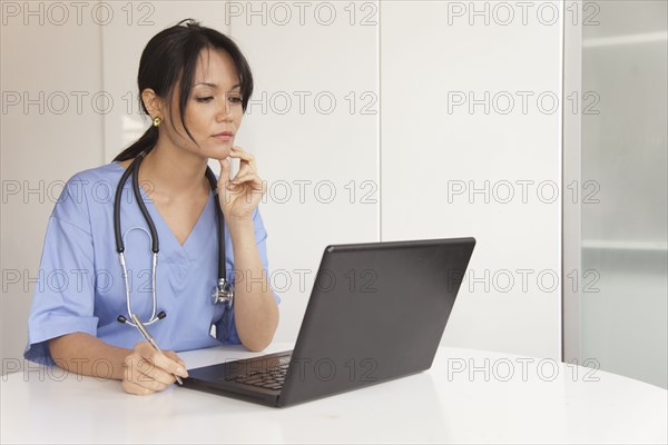 Mixed race doctor using laptop