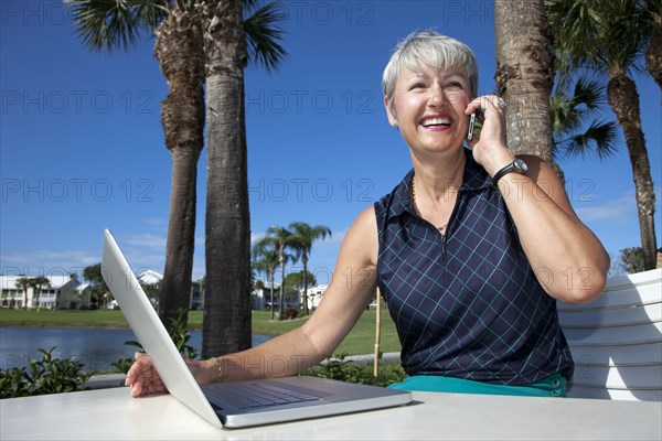 Caucasian woman talking on telephone and using laptop
