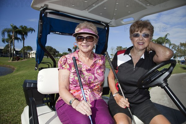 Senior Caucasian woman riding in golf cart