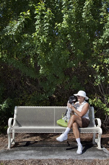 Caucasian woman sitting on park bench with dog