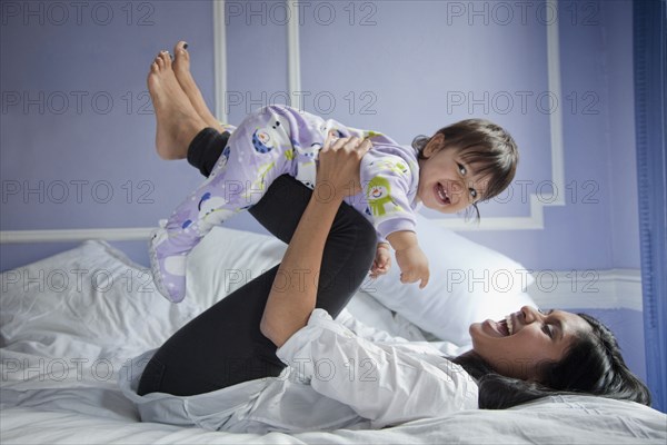 Sri Lankan mother playing with baby girl on bed