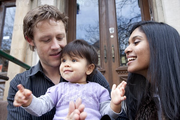 Parent's sitting on front stoop with baby girl