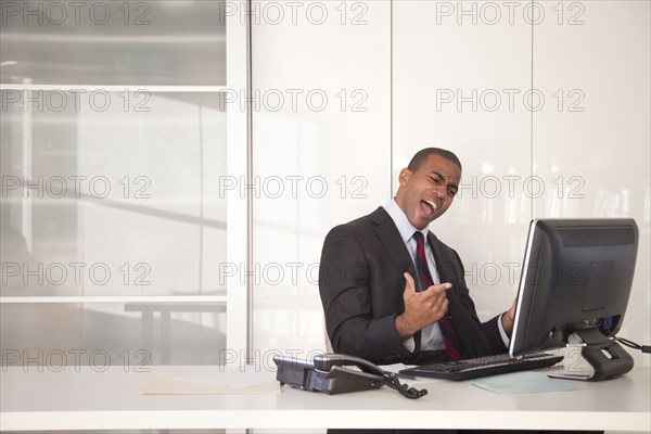 Black businessman cheering at desk