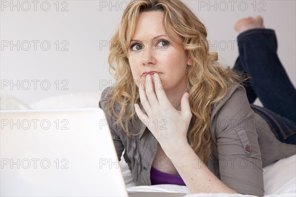 Caucasian woman laying on bed using laptop