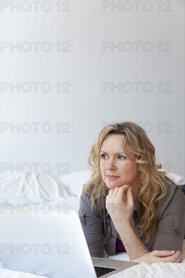 Caucasian woman laying on bed using laptop