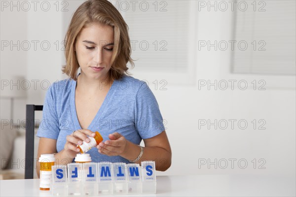 Caucasian woman putting pills into organizer
