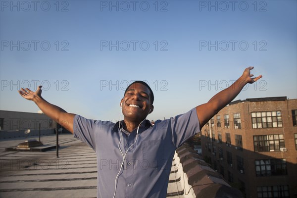 Black man with arms outstretched on rooftop