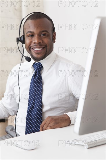 Black businessman in headset working at desk