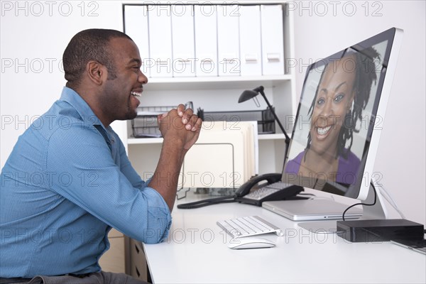 Black businessman talking to co-worker over computer