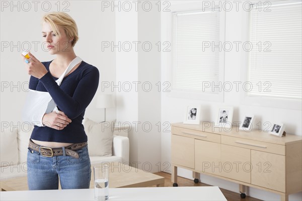 Caucasian woman with broken arm reading pill bottle