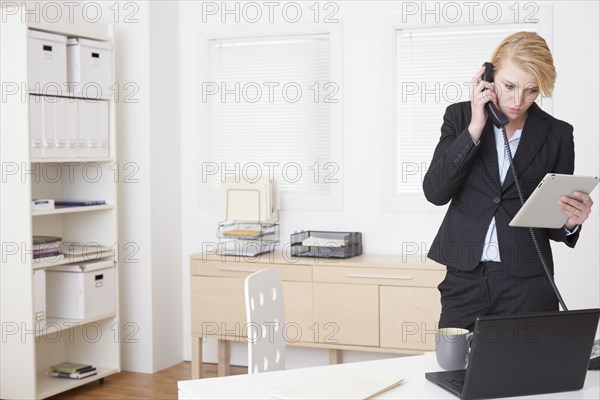 Caucasian businesswoman talking on phone in office