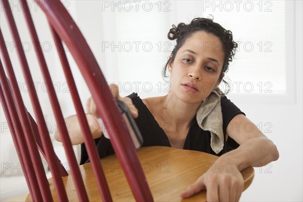 Hispanic woman sanding chair