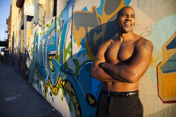 Bare chested African American man standing on city street