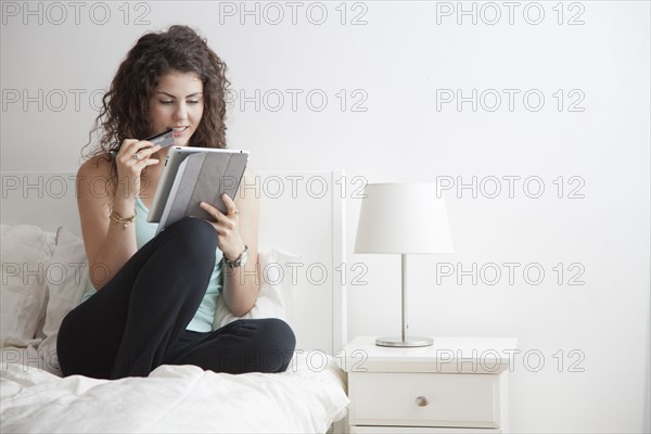 Caucasian woman using digital tablet in bed