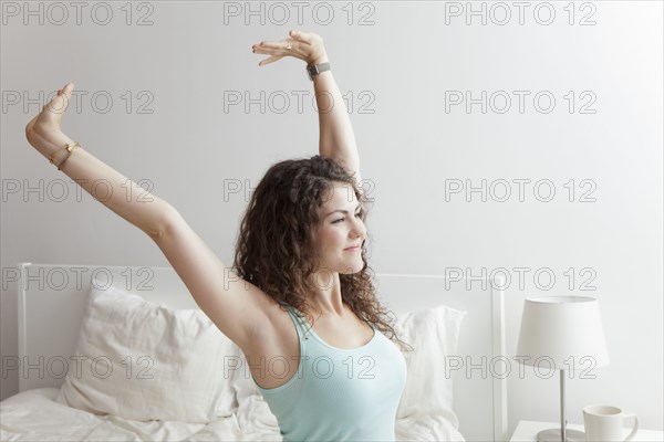 Caucasian woman stretching in bed