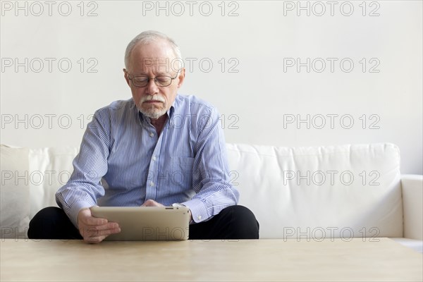 Caucasian man using tablet computer on sofa