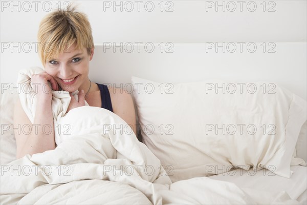 Caucasian woman smiling in bed