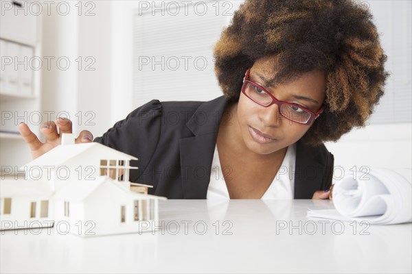African American businesswoman working on model of house