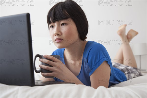 Chinese woman using laptop on bed