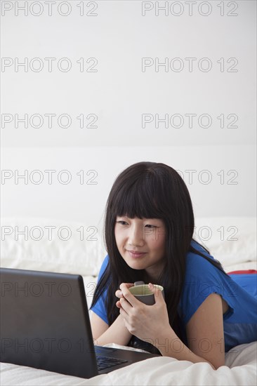 Chinese woman using laptop on bed