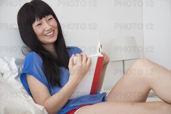 Chinese woman reading book on bed