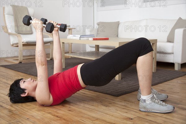 Woman lifting weights in living room