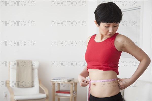 Woman measuring her waist in living room