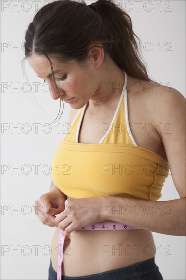 Caucasian woman measuring her waistline